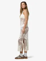 Vestido largo sin mangas confeccionado en encaje color crudo con diseño floral repetido en toda la superficie. Escote redondo y calce estándar. Prenda semi transparente.