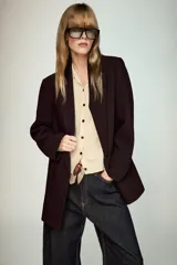 Chaqueta de punto de corte clásico, color gris, con cuello solapa, manga larga y cierre frontal con botones a contraste.
