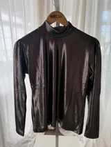 Polera de manga larga con acabado brillante color peltre, cuello alto y frunces sutiles en los hombros.