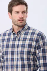 Camisa de manga larga con estampado de cuadros en tonos azul, beige y naranja. Presenta cuello abotonado, cierre frontal con botones y un bolsillo pequeño en el pecho.