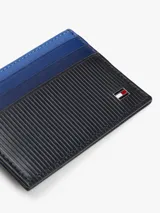 Tarjetero Tommy Hilfiger de diseño compacto y ultraplano, confeccionado en piel genuina. Presenta una combinación de colores en azul y negro con textura acanalada en la parte inferior y el logo de la bandera de la marca aplicado en metal.