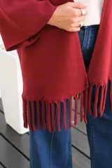 Saco abierto tipo capa en color bordó, confeccionado en tejido de punto suave, con mangas amplias y detalle de flecos en el ruedo.