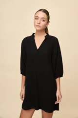 Vestido corto negro de silueta relajada, con escote en V y mangas 3/4 levemente abullonadas.