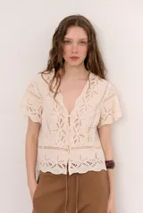 Camisa azul de manga corta confeccionada en tejido broderie con diseño calado y floral. Cuenta con escote en V y cierre frontal de botones.