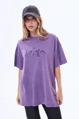 Remera de algodón con efecto lavado, color violeta, de corte oversize y manga corta. Presenta un estampado lineal en el pecho con dibujos de una botella, una fresa, una copa, un florero y una fruta.