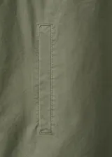 Parka verde militar de algodón, de diseño oversize con cuello camisero, manga larga, bolsillos con solapa en el pecho, bolsillos laterales y cordón ajustable en la cintura.