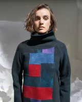 Sweater de lana merino afieltrada color verde oscuro con cuello alto y diseño de bloques de color en azul, rojo y violeta.