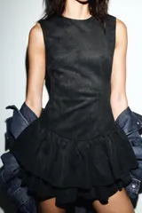 Vestido corto de cuello redondo y manga sisa, confeccionado en tejido efecto ante. Presenta un diseño ajustado en el torso con bajo acabado en doble volante. Cierre posterior con cremallera.