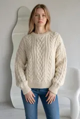 Sweater de punto grueso color rojo, con diseño de trenzas verticales, cuello redondo y puños acanalados.