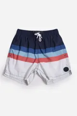 Short de baño celeste con estampado de hojas pequeñas en tonos verdes y blancos. Cuenta con cintura elástica con cordón ajustable, bolsillos laterales y un parche circular con logo en la parte inferior.