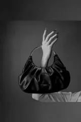 Cartera color rosado con frunces y asa metálica circular. Incluye correa de hombro ajustable.