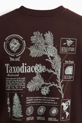 Buzo marrón de corte holgado con cuello redondo, confeccionado en mezcla de algodón. Presenta un estampado gráfico frontal con motivos botánicos y la inscripción "Taxodiaceae". Cuenta con puños y bajo acanalados.