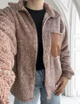 Campera de abrigo tipo teddy color camel, con cierre frontal y bolsillo de cuero sintético en el pecho.