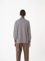 Sweater azul de cuello alto, con mangas amplias y puños ajustados.