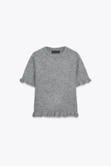 Jersey de punto de cuello redondo y manga corta, con detalle de volantes en las mangas y en el ruedo.