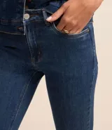 Pantalón de jean azul, corte slim, con trabillas en la cintura, bolsillos, cierre delantero tradicional y abertura en el bajo.