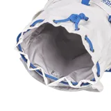 Mochila de lona blanca con base azul, cierre con cordón ajustable, bolsillo frontal con cierre y logo de New Balance en azul y rojo.