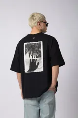 Remera color crudo, corte oversize, mangas cortas y cuello redondo. Estampado frontal con dos árboles unidos por sus raíces y parche estampado en la espalda con una silueta de mano que se fusiona con ramas.