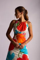 Vestido largo con estampado de flores en tonos naranja, rojo, verde y celeste. Tiene escote halter, espalda descubierta y aberturas en la cintura.