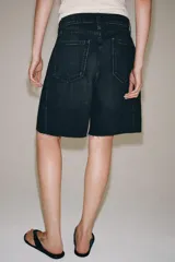 Bermuda de denim color bordó, de tiro medio y corte relaxed, con diseño de cinco bolsillos, trabillas para cinto y bajo desflecado.