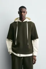 Sudadera de corte oversize confeccionada en tejido técnico de algodón con elasticidad, cuello redondo y manga corta. Presenta una tacha metálica decorativa en la parte posterior.