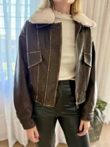 Campera de eco cuero en tono marrón con efecto desgastado, corte oversize y cierre frontal. Presenta costuras marcadas, bolsillos frontales y puños con botones.