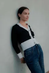 Saco tipo cardigan bicolor con diseño de bloques en blanco y negro, cuello en V, cierre frontal con botones y mangas largas con puños ajustados.