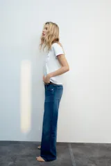 Camiseta blanca de algodón con cuello redondo, manga corta y bolsillo en el pecho que incluye un texto impreso a contraste.
