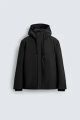 Cazadora técnica regular fit de color negro, con interior ligeramente acolchado. Presenta cuello subido con capucha ajustable, cierre frontal de cremallera oculta por solapa con botones a presión, bolsillos laterales y puños con interior de rib.