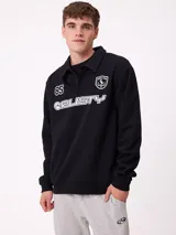 Buzo tipo polo de manga larga, confeccionado en tejido de algodón y poliéster. Presenta cuello camisero con cierre de botones, puños y ruedo acanalados. Incluye estampados gráficos en el frente con el logo de la marca y el número 85.