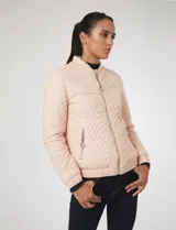 Campera bomber capitoneada color rosa pastel, con diseño acolchado en chevrón, cuello mao, cierre frontal y bolsillos laterales con tiradores metálicos circulares.