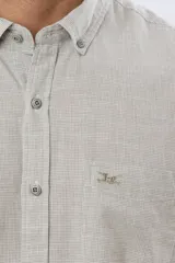 Camisa de lino de manga corta con sutil patrón de cuadros pequeños, cuello camisero abotonado, bolsillo en el pecho con logo bordado y cierre frontal de botones.