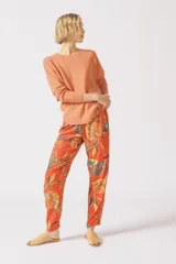 Pantalón de viscosa color naranja con estampado de hojas y lunares.