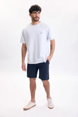 Camiseta de manga corta celeste con cuello redondo y pequeño bordado de una ola en el pecho.