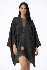 Ruana tejida de punto en algodón y lurex, color negro con hilos brillantes. Diseño abierto con cuello en V y corte asimétrico. Incluye etiqueta de cuero sintético con la inscripción "PURA LANA".