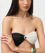 Top de bikini bandeau de microfibra con diseño color block en color negro y blanco, fruncido central y detalle metálico.