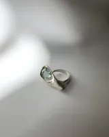 Anillo de plata 950 de diseño orgánico, con una gema de topacio facetada en tono celeste claro incrustada en un volumen envolvente.