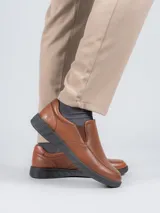 Zapato tipo slip on Hush Puppies de cuero color marrón, con suela negra de poliuretano con tecnología Spinal y plantilla Dual Fit.