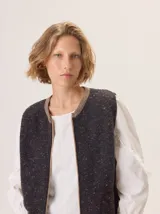 Chaleco de tejido de punto con textura jaspeada en color gris oscuro, con cierre frontal y terminaciones en tono contrastante.