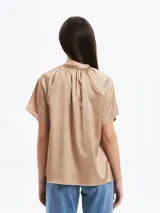 Blusa de satén color tostado con cuello redondo, cierre frontal con cordones ajustables y mangas cortas tipo raglán con diseño holgado.