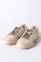 Championes urbanos de gamuza color marrón, con suela de goma en tono crema y cordones jaspeados. Presenta un refuerzo en la puntera y un detalle en cuero beige en el talón.