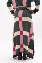 Pollera midi de tejido de punto con diseño geométrico de cuadros en tonos verde, rosa y beige. Presenta cintura elástica con cordón de ajuste y aberturas laterales en el ruedo.