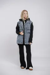 Chaleco oversize de jean celeste con cuello clásico, cierre frontal con botones metálicos, dos bolsillos con solapa en el pecho y corte a la cadera. Sin mangas.