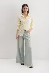 Camisa de corte clásico con cuello camisero, manga larga con puños abotonados y cierre frontal con botones. Presenta un diseño de rayas verticales finas en color negro sobre fondo blanco.