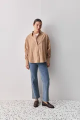 Camisa celeste de corte oversize, con mangas largas, cuello camisero y cierre frontal de botones.