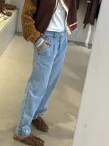 Jean de corte gaucho en color azul, con diseño de pinzas en la cintura, tiro medio y detalle de ajuste con botón en el ruedo.