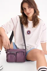 Bandolera color violeta con múltiples bolsillos frontales con cierre y correa ajustable negra.