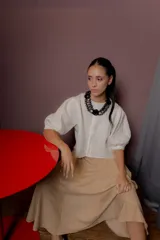Blusa de lino color crudo con silueta estructural, cuello redondo, cartera oculta con botones de nácar y mangas cortas abullonadas con tablas.