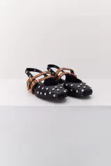 Balerina negra de cuero con punta fina y dos correas marrones con hebilla sobre el empeine. Decorada con tachas plateadas.