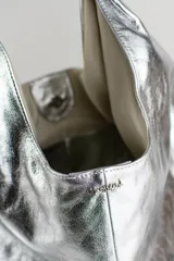Cartera de cuero vacuno con pelo en diseño animal print similar a piel de ciervo, silueta triangular y asa integrada.